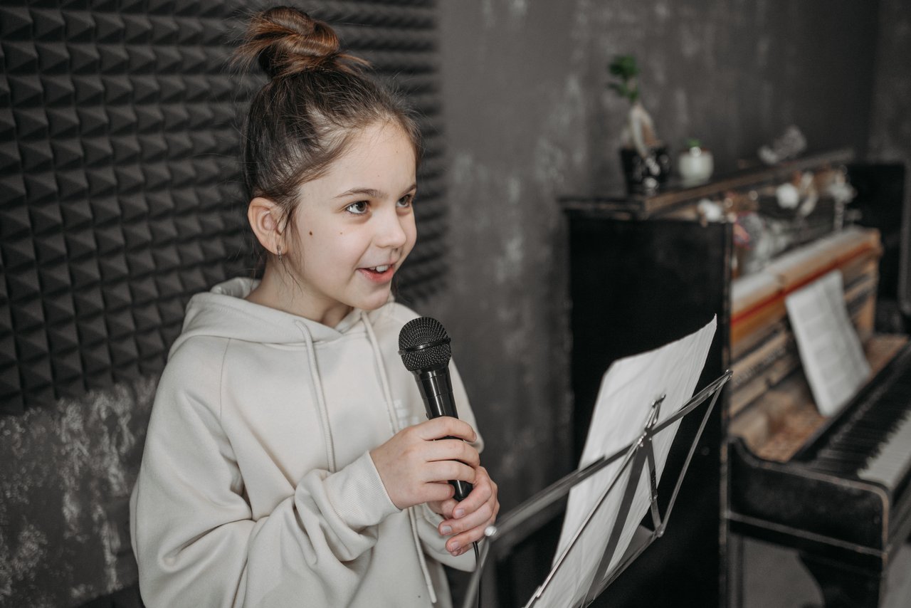 Crafting Captivating Headlines: Your awesome post title goes here Caucasian girl singing into a microphone in a soundproof studio with sheet music and piano.
